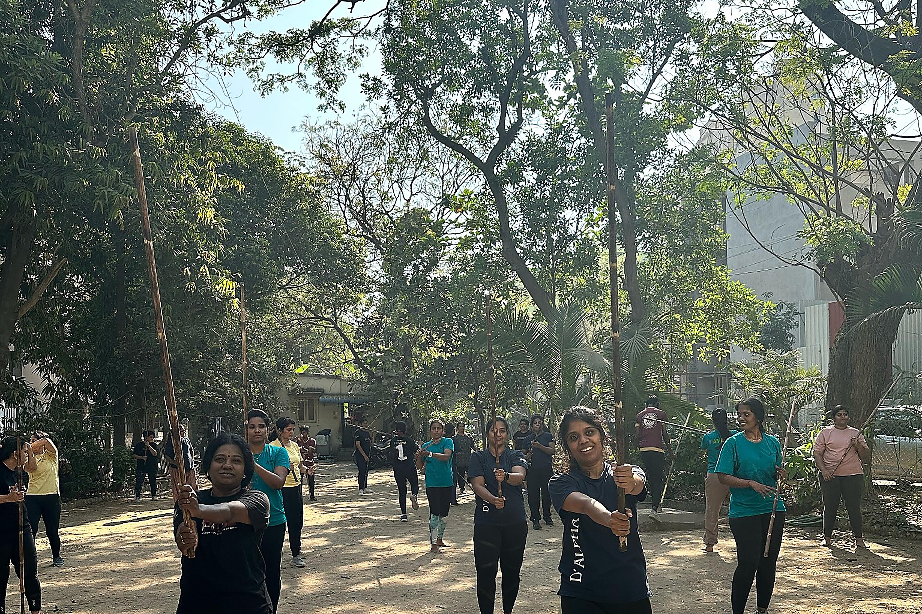 Women training Silambam staff fighting in outdoor park session at H3A